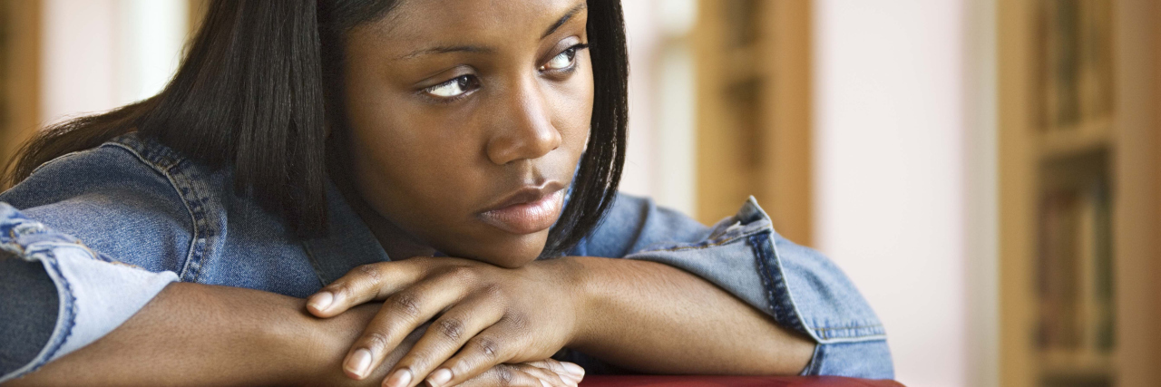 Experiencing Low Self-Esteem Because You're Sick young woman looking to the side with her head on her hands