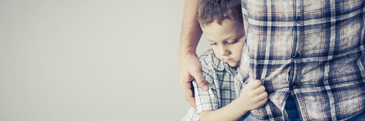 What It's Like Being a Father With a Chronic Illness son hugging his dad's waist, father holding his son's shoulder