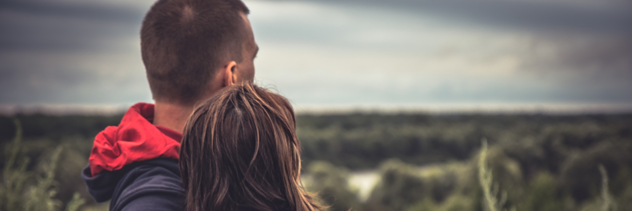 How the U.K. Disability Benefits System Penalizes Relationships Young couple embracing in a field.