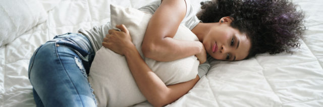 an african american woman hugging her pillow on a bed