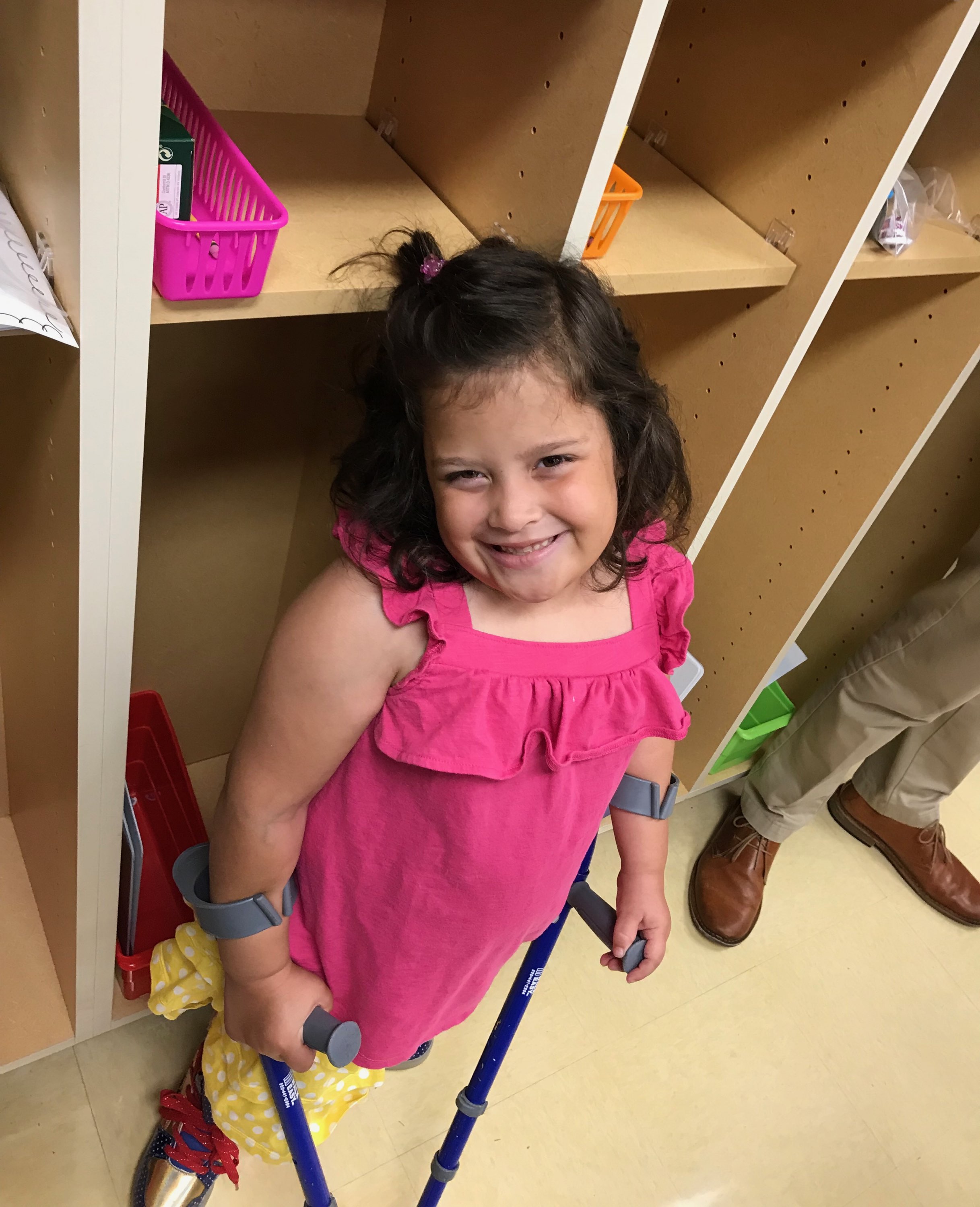 Little girl at school standing with her crutches.