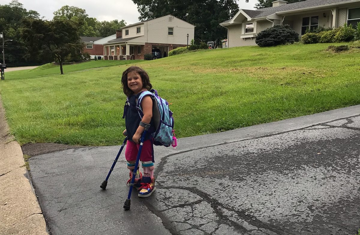 Waiting at the end of the driveway for the bus; girl who uses lofstrand crutches