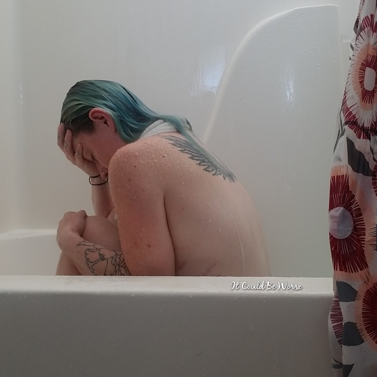 photo of contributor, a woman with green coloured hair, sitting in bath with hand resting on forehead