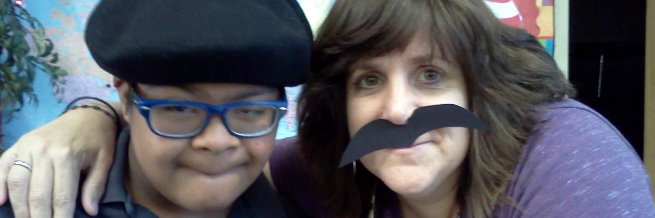 Why Teachers Need an Open Heart Towards Students With Disabilities Selfie of child with a disability and teacher. Teacher is wearing a fake mustache.