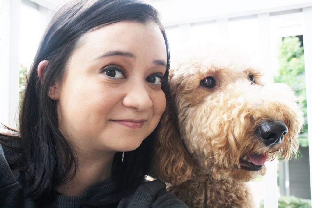 woman with black hair next to fluffy dog