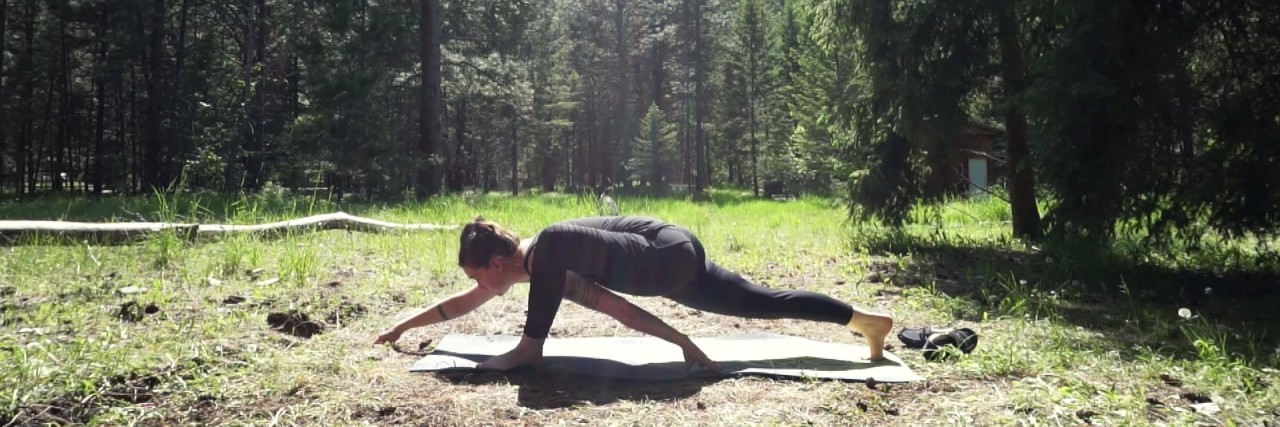 Learning to Appreciate My Body With Chronic Illness and Yoga photo of woman in forest in lizard pose