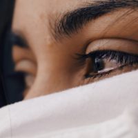 Una mujer triste. Solo se ven sus ojos. Esta lagrimeando; sus ojos son cafes