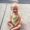 Little girl with Down syndrome sitting on floor smiling at camera