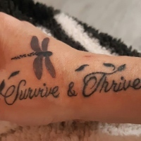 Jennifer's hand tattoo which reads "Survive and Thrive" and a dragonfly on it.