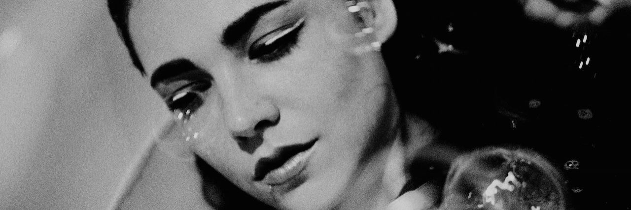 A black and white portrait of a woman sitting in a bathtub