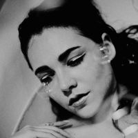 A black and white portrait of a woman sitting in a bathtub