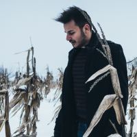 photo of man standing in winter cornfield