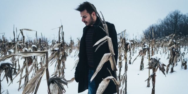 photo of man standing in winter cornfield