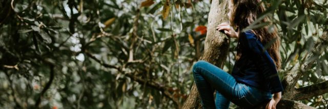 photo of young girl climbing a tree