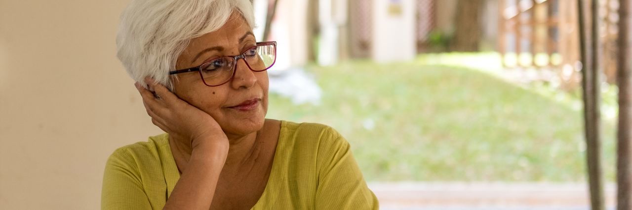 Why Cancer Survivor Guilt Is Understandable but Not Justified woman sitting at table resting head on her hand
