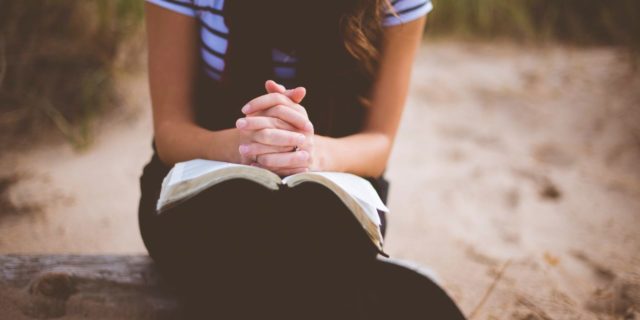 8 Things I Learned About Trauma After Being Diagnosed With a Chronic Illness focus on woman sitting on a log with her hands folded over a book