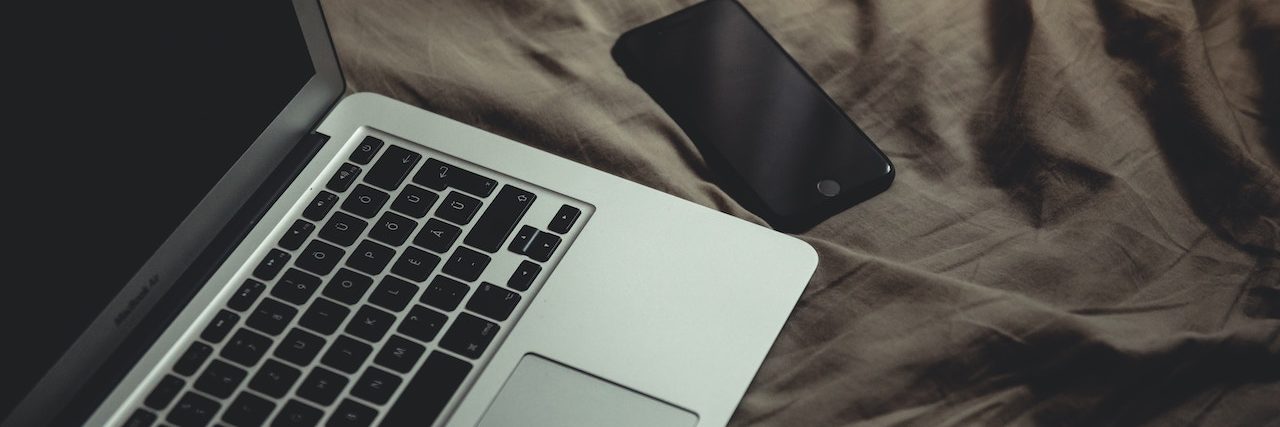 Work-From-Home Jobs for People With Disabilities and Chronic Illnesses Open laptop and cellphone on brown bedsheet