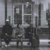 black and white photo of group of people waiting for train or bus