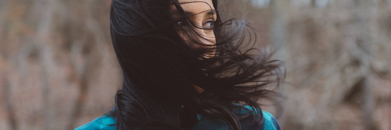 Living With Emetophobia When People Don't Take It Seriously photo of woman with dark hair in woods with hair covering her lower face