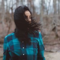 photo of woman with dark hair in woods with hair covering her lower face