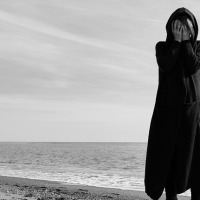 woman standing on beach with her hands over her face
