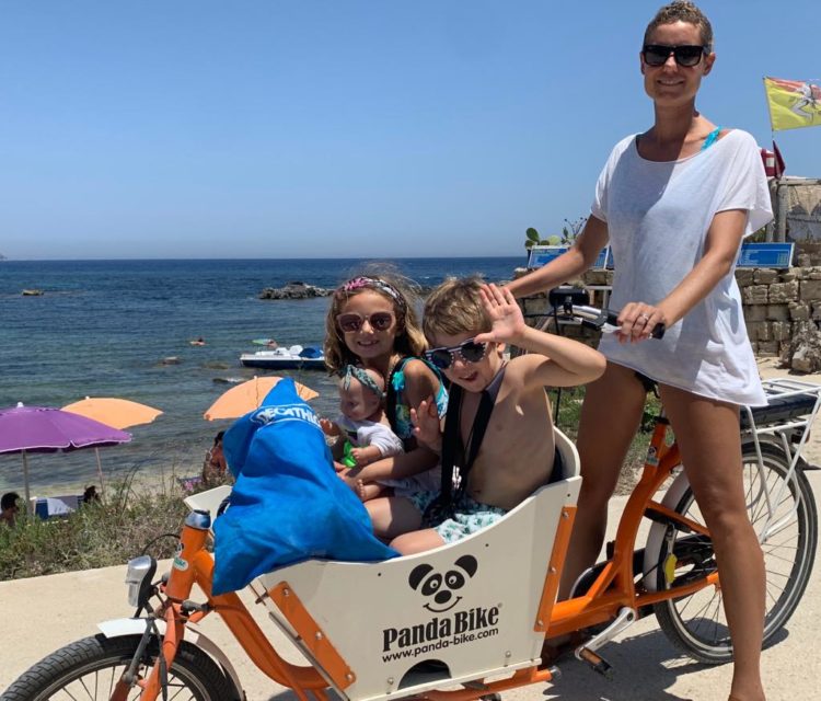 mom biking with two small kids in front seat