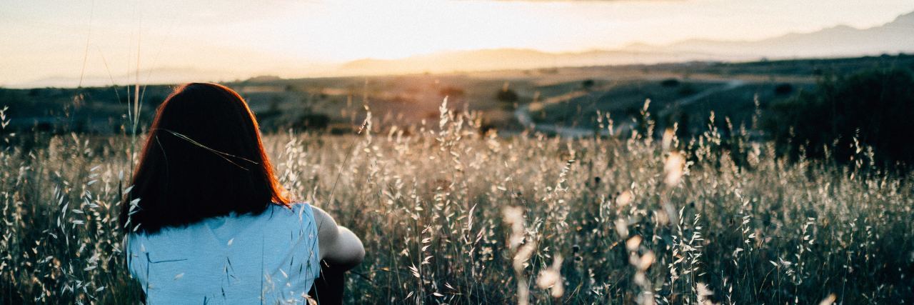 Being Chronically Ill and Wishing for a Healthy Body woman sitting in a field while the sun is setting