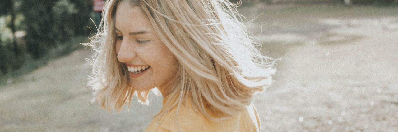 What to Know If You Can't Take Pride in Your Therapy Wins photo of blonde woman smiling in bright light outdoors