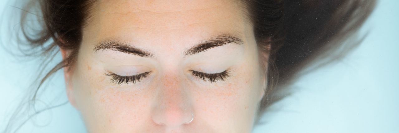 photo of woman underwater with eyes closed and hair floating above her