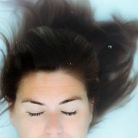 photo of woman underwater with eyes closed and hair floating above her