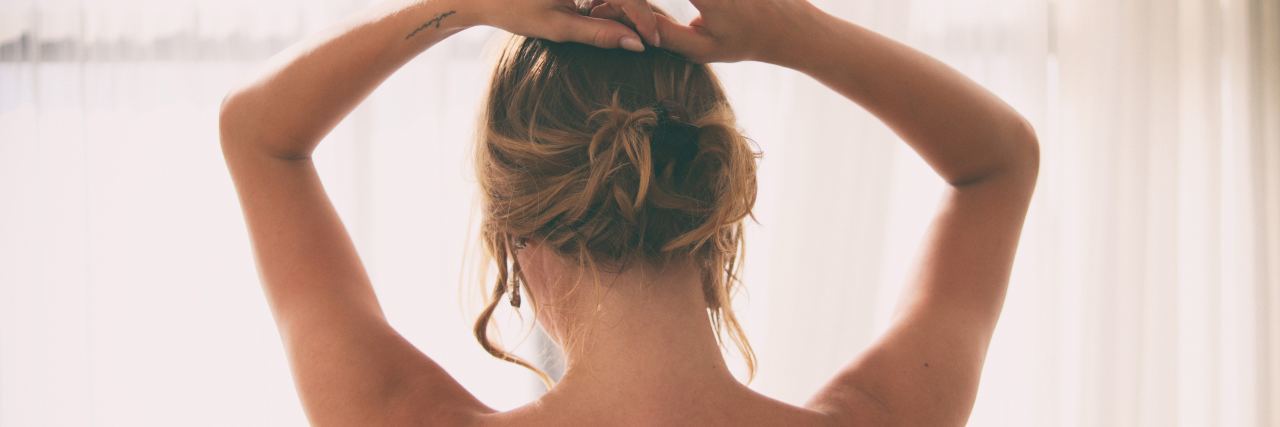 photo of woman from behind raising hands to hair