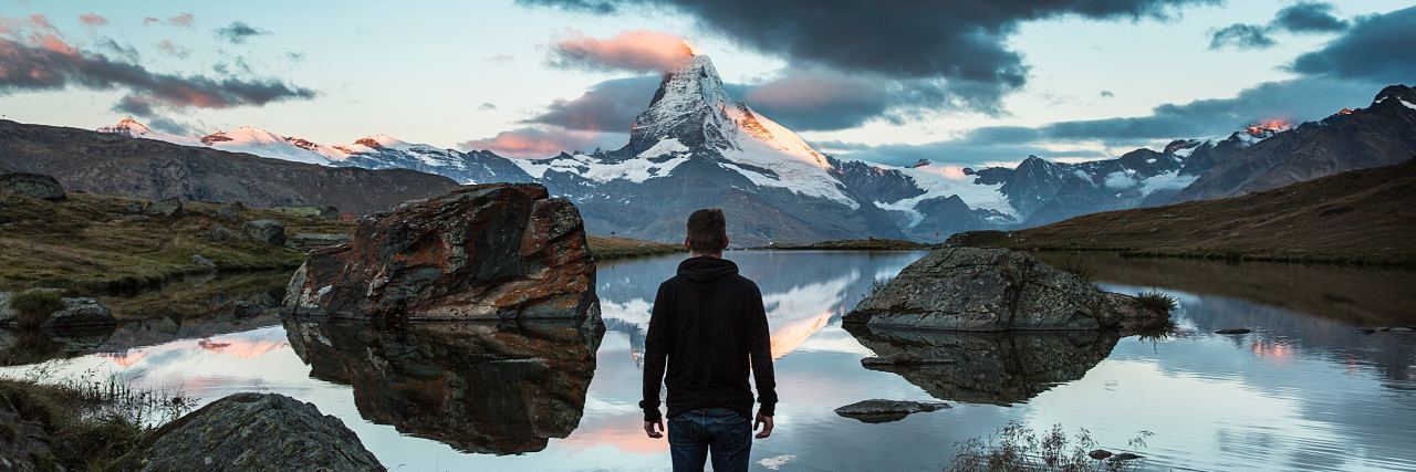 man standing in front of distant mountain