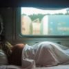 woman laying in bed next to a window