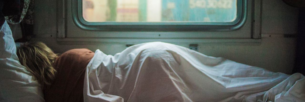 Why I'm Trying to Accept the Limitations That Come With Being Sick woman laying in bed next to a window