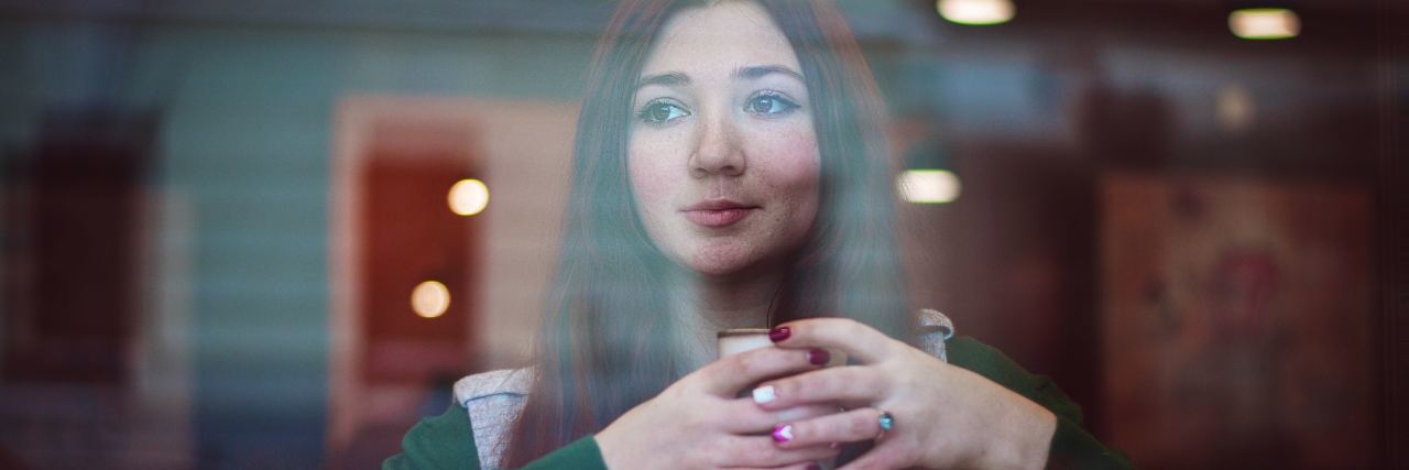 The Surprising Link Between My Digestive Disease and My Eating Disorder photo of dark haired young woman in coffee shop with coffee and croissant