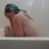 photo of contributor, a woman with green coloured hair, sitting in bath with hand resting on forehead