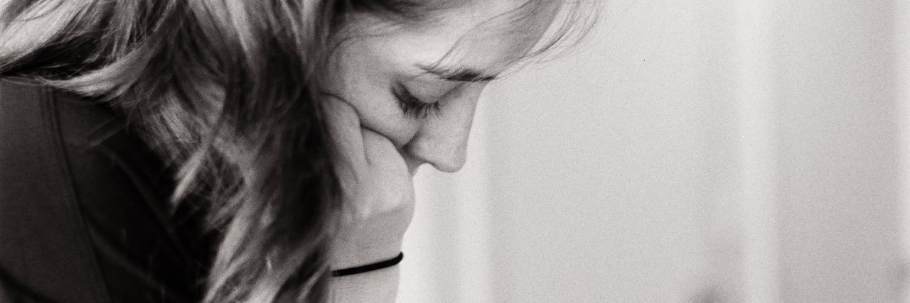 I Didn't Realize Mental Illness Made Me Feel Lonely black and white photo of woman with head rest on hand and eyes closed