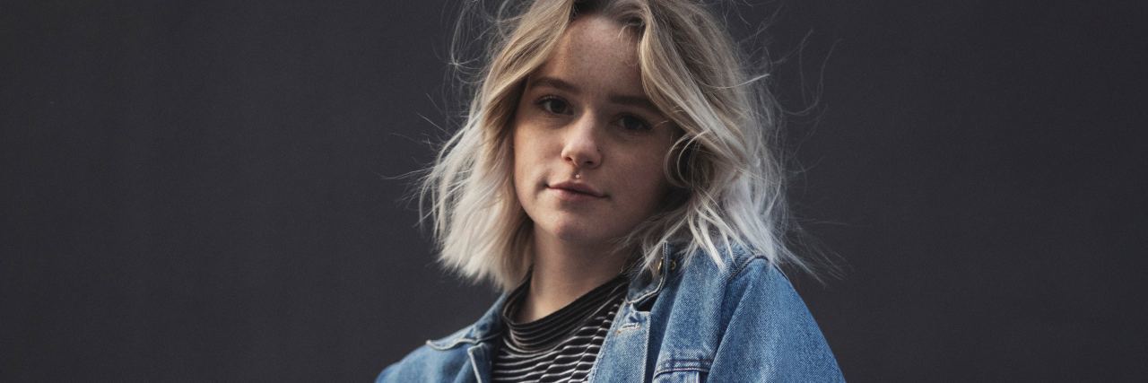 People Living With Mental Illness Are Just as 'Normal as Everyone Else portrait photo of blonde woman with hands in pockets looking into camera