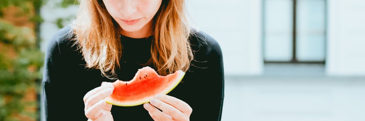 What 'Safeguarding Nutrition' Means in Eating Disorder Recovery photo of young woman holding and looking down at a partially eaten melon