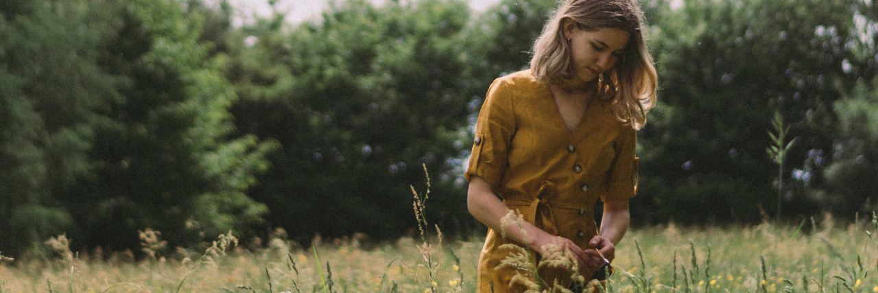 photo of blonde woman in yellow dress standing in field of wildflowers