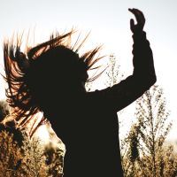 photo of woman's silhouette celebrating in field or trees