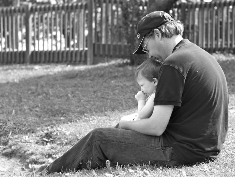 David holding his daughter, sitting in the grass