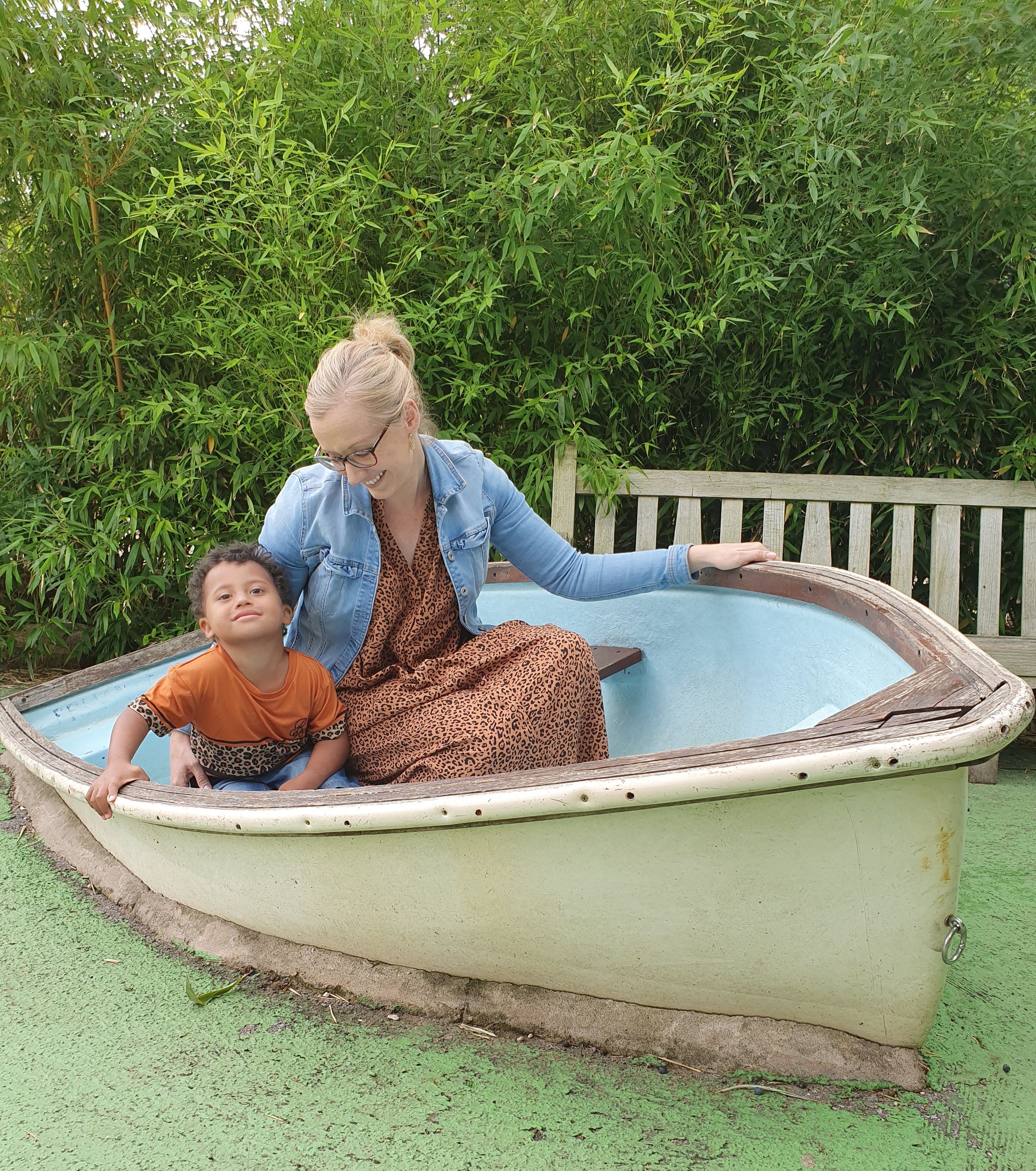 Hayley sitting in an old boat in the grass with her son.