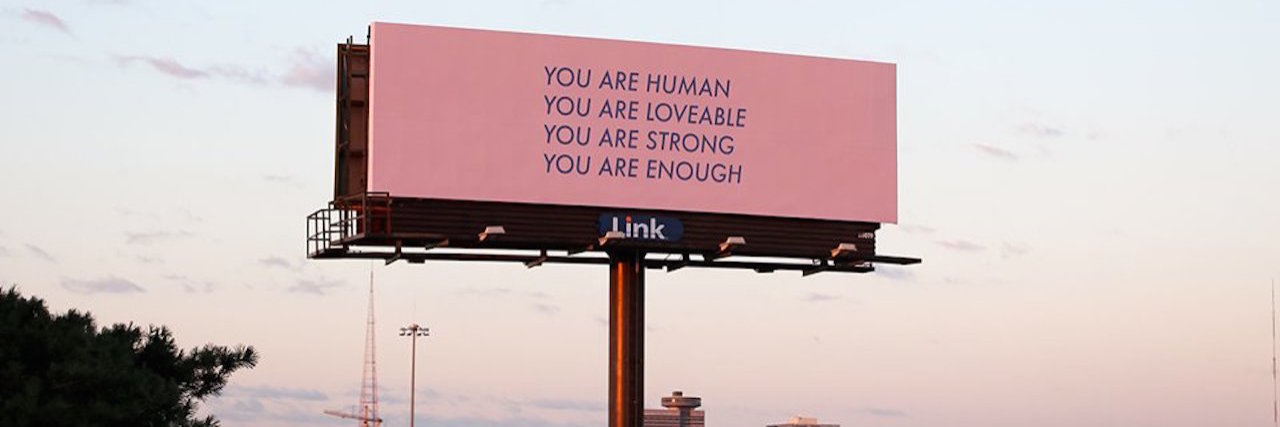 A pink billboard with the words: You are human, you are loveable, you are enough