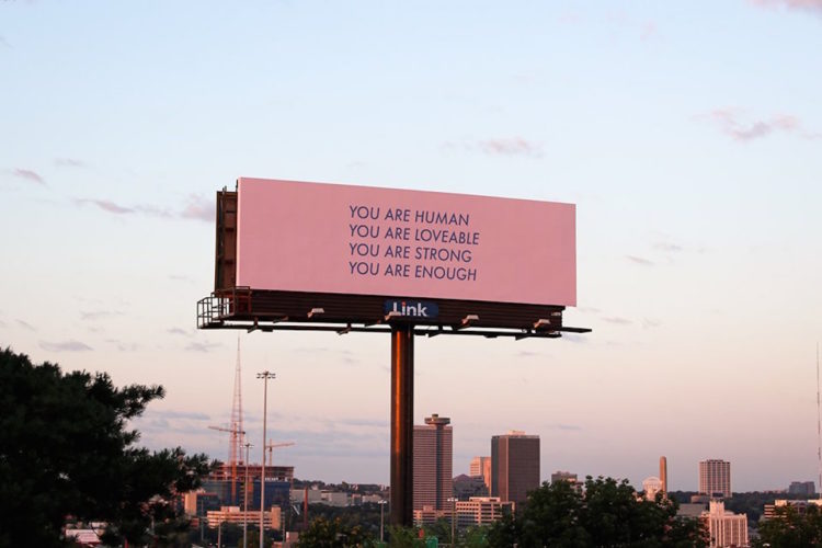 A pink billboard with the words: You are human, you are loveable, you are enough