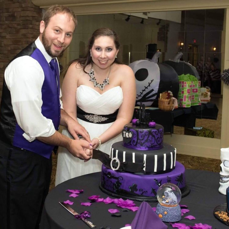 bride and groom cutting purple and black wedding cake