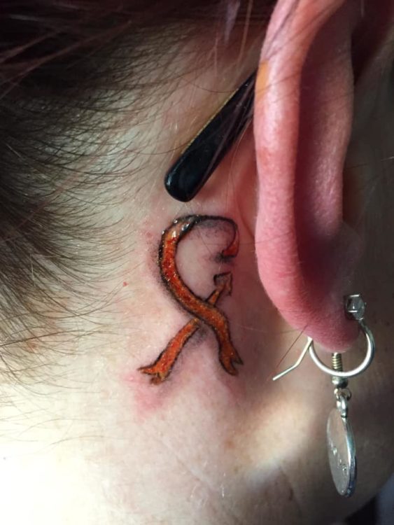 red awareness ribbon tattoo behind ear