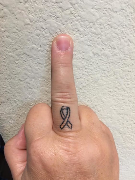 small awareness ribbon tattoo on middle finger