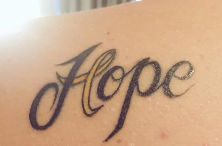 tattoo on arm that says hope with part of the h looking like an awareness riboon