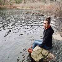 Jennifer sitting by a lake.